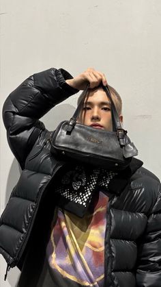 a man in a black puffer jacket holding his purse over his head