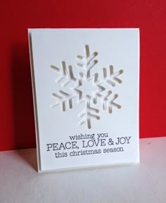 a white card with a snowflake design on the front, and words saying wishing you peace, love & joy this christmas season