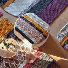 the table is covered with colorful knitted placemats and dishes on top of it