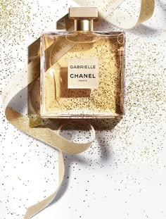 a bottle of chanel perfume sitting on top of a white table next to a ribbon