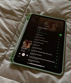 a tablet sitting on top of a bed covered in white sheets and green trims