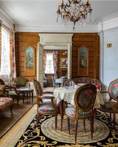 an ornate dining room with fancy chairs and table cloths on the rug, chandelier hanging from the ceiling