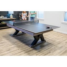 a ping pong table with two people standing in the background and one person looking at it