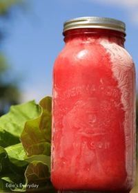 a red mason jar sitting on top of a green leafy plant next to a blue sky