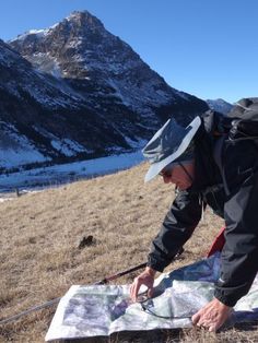 a man is looking at a map in the mountains