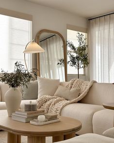 a living room filled with furniture and a large mirror on the wall above it's windows