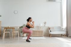 a woman is doing squats in the living room