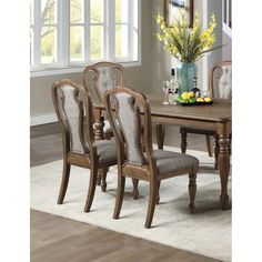 a dining room table with chairs and a vase filled with flowers on top of it