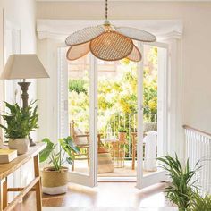 a living room filled with lots of plants next to an open patio door and french doors