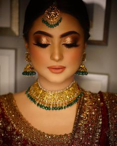 a woman wearing gold and green jewelry