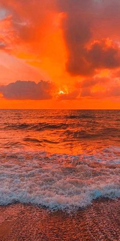 an orange sunset over the ocean with waves