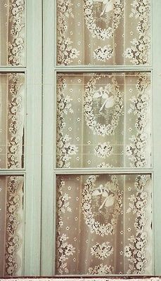 an old window with curtains and flowers on it