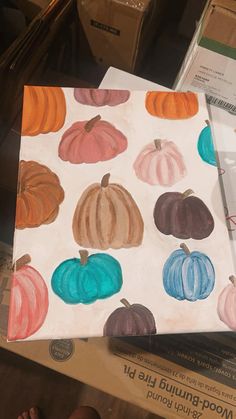 a painting of colorful pumpkins on a white paper with blue, orange and green colors