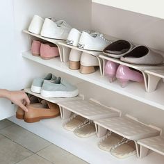 a person reaching for shoes on shelves in a room with white walls and tile flooring