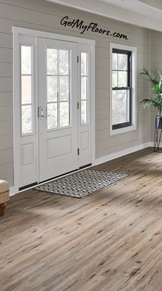 a living room with white walls and wood floors, two doors leading to the front door