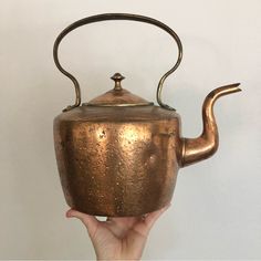 a hand holding an old teapot with a handle