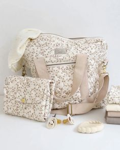 a white purse and two matching bags are on the table next to some other items