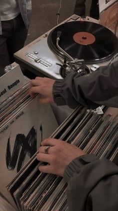 a person holding a record player in front of a bunch of records on a table