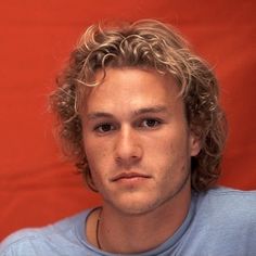 a young man with curly hair is looking at the camera