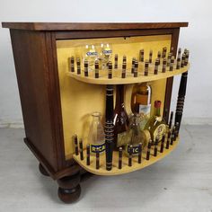 a wooden shelf with bottles and glasses on it's sides, in front of a white wall