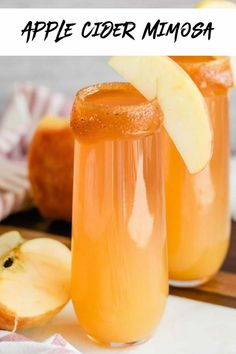 two glasses filled with apple cider on top of a cutting board