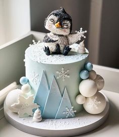 a cake decorated with snowflakes, frosting and a penguin figurine