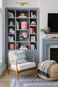 a living room with blue bookcases and a white chair in front of a fireplace