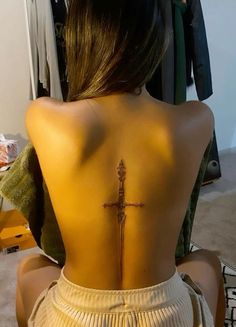 the back of a woman's body with a cross tattoo on her lower back