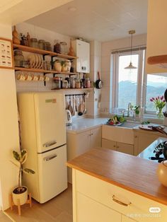 a white refrigerator freezer sitting inside of a kitchen next to a sink and window