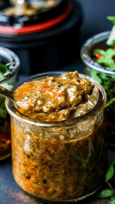 a jar filled with food sitting on top of a table next to some salads