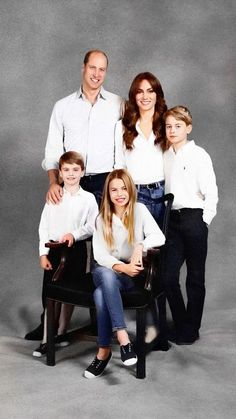 a family is posing for a photo in their white shirts and black pants, with one child sitting on a chair