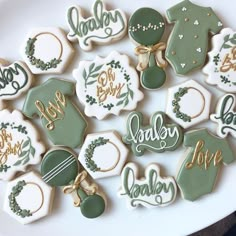 decorated cookies are arranged on a plate with the word baby spelled in gold and green