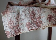 a red and white flowered bed spread on top of a wooden chair