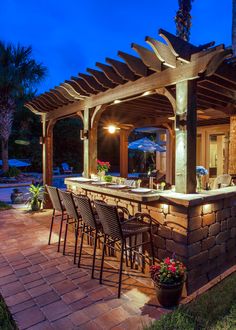 an outdoor bar with lots of chairs and lights on it's outside patio area