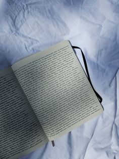 an open book sitting on top of a white sheet