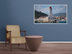 a room with a chair and a painting on the wall that has a lighthouse in it