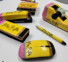 some pens and pencils are sitting on a table with erasers in the shape of school supplies