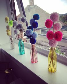 four vases filled with colorful pom - poms on a window sill