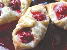 four pastries with jelly on them sitting on a glass plate, ready to be eaten