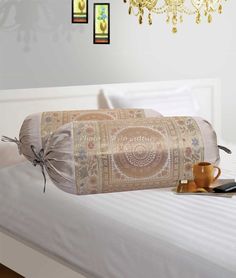 a white bed topped with a large pillow next to a chandelier