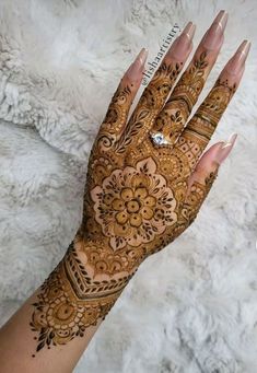 a woman's hand with henna tattoos on it, showing the intricate design