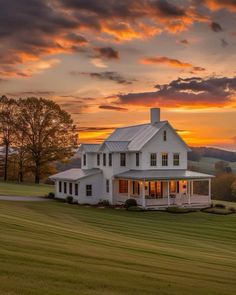 a large white house sitting on top of a lush green field under a cloudy sky