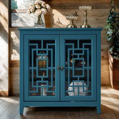 a blue cabinet sitting on top of a wooden floor next to a potted plant