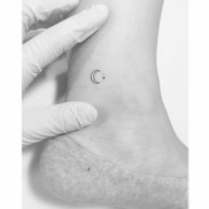 a woman's foot with a small crescent tattoo on her left ankle, and the moon