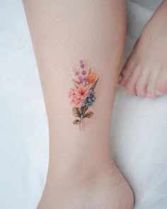 a woman's foot with flowers painted on the lower part of her leg and ankle