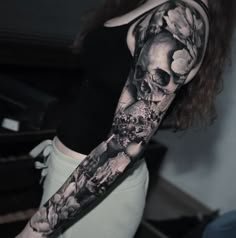 a woman's arm with a skull and flowers tattoo on her left arm, while the other half sleeve is black and white