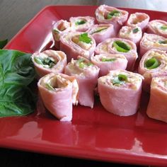 a red plate topped with lots of food on top of a green leafy table