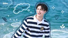 a young man standing on top of a beach next to the ocean wearing a striped shirt