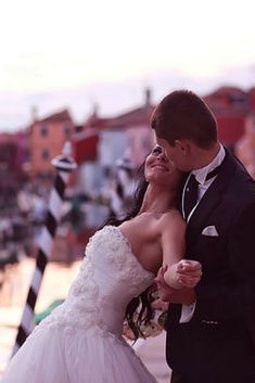 a bride and groom are posing for a wedding photo in front of an italian cityscape