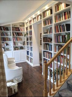 a living room filled with lots of books on top of white shelving unit units